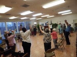 Senior adults engaging in seated exercise activities in a community center.