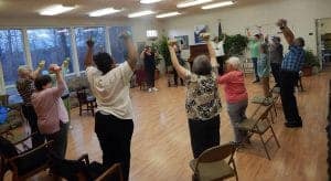 Accessible yoga class with diverse participants stretching in a bright, welcoming studio.