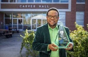 Celebrating 25 Years Award at CAES News, Carver Hall, with a smiling man in a green shirt and blazer.