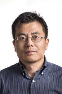 A man wearing glasses and a dark blue striped shirt looking directly at the camera.