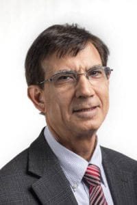Expert male professional in business attire, wearing glasses, smiling confidently.