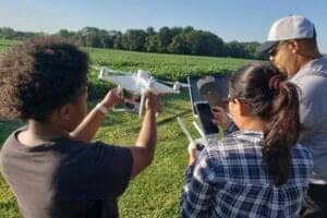 Aerial drone operator demonstrating drone technology to a diverse group outdoors.