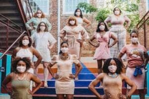 A woman-led diverse group of women wearing face masks standing confidently on outdoor stairs.