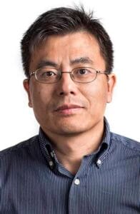 A man wearing glasses and a striped shirt looking directly at the camera.