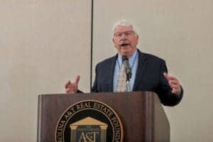 A man speaking at a podium during a conference or event.