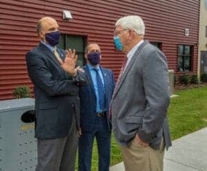 Engaged professionals in face masks having a conversation outdoors at CAES News event.