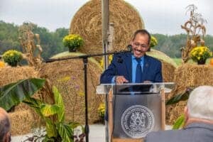 Innovative agricultural event with a speaker at a podium outdoors, surrounded by hay bales and plant.