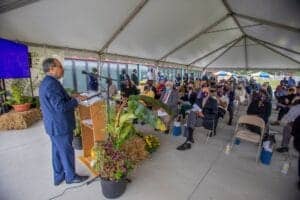 Business conference with speaker addressing an audience under a large tent.