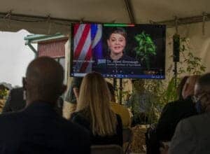 Empowered woman speaking at a virtual conference on a large screen during a professional event.