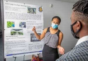 Environmental science student presenting research poster at academic conference.