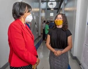COVID-19 safety measures: two women wearing face masks having a conversation in a professional setti.