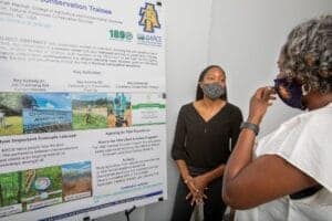 CAES News conference with a woman presenting to an attendee wearing a mask.