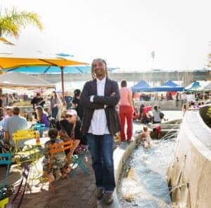 Enjoying a sunny day at an outdoor event with colorful seating, water features, and a lively crowd.