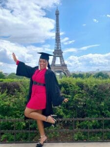 Graduation student celebrating in front of the Eiffel Tower in Paris, France.