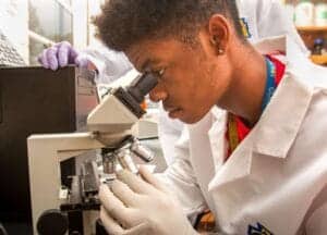 Young scientist examining samples with a microscope in a laboratory setting.