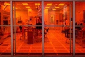Laboratory or research facility with orange-tinted glass walls and scientific equipment inside.