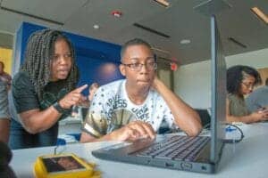 Engaged students collaborating on a laptop in a modern classroom setting.