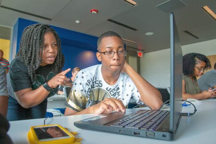 Engaged students collaborating on a laptop in a modern classroom setting.