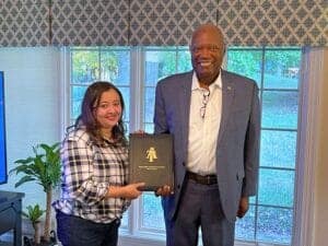 Woman receiving award from man in formal setting at CAES News event.
