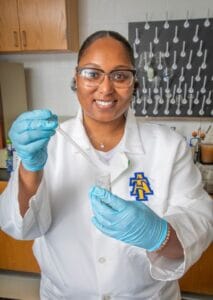 Female scientist in lab coat with pipette and test tube in laboratory setting.