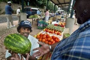 Watermelon being handed over at a local outdoor market in a community setting.