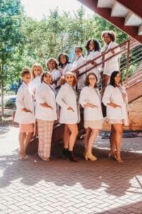 A woman teacher with a diverse group of young students outdoors on a school trip.