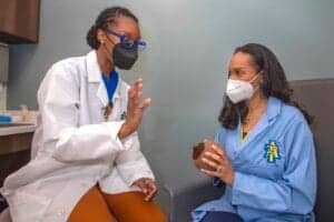COVID-19 vaccination consultation between healthcare professionals and patient in clinic.