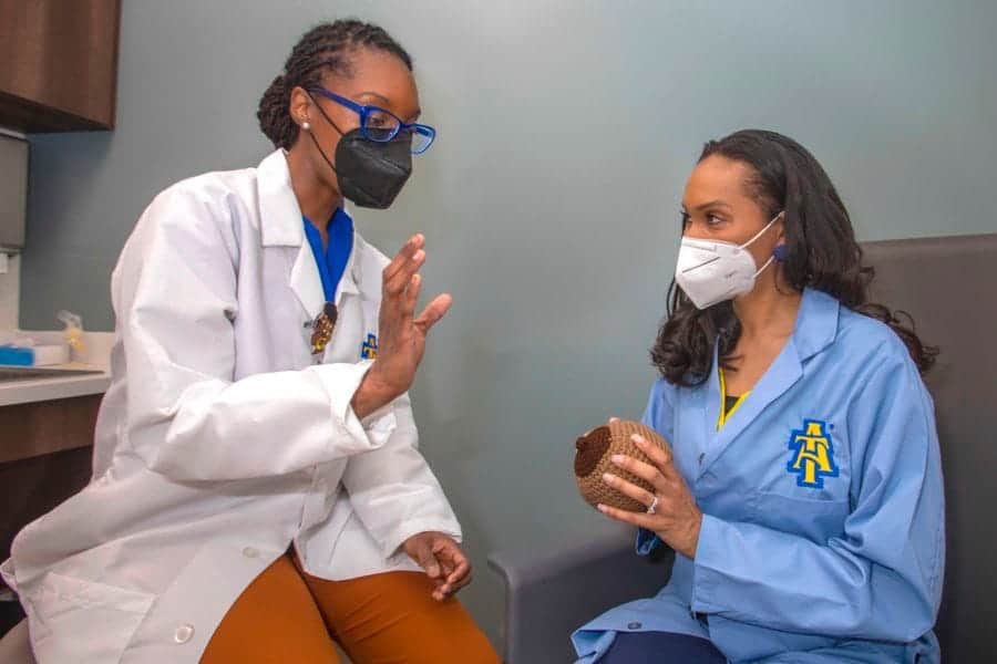 COVID-19 vaccination consultation between healthcare professionals and patient in clinic.