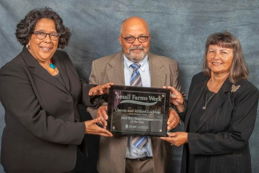 Celebrating Small Farms Week award with three professionals holding a plaque.