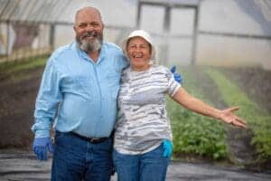 Planting and gardening enthusiasts smiling in a greenhouse.