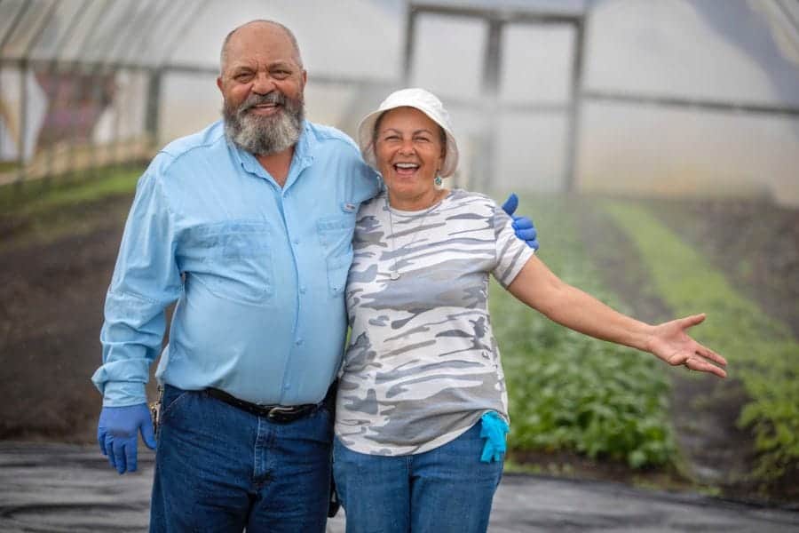 Planting and gardening enthusiasts smiling in a greenhouse.