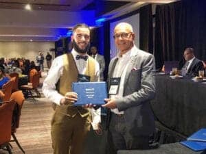 High-achieving professional receiving award at conference event in a formal setting.
