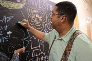 Engaged man writing on a chalkboard with colorful chalk, promoting education and learning.