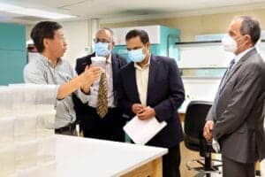 Business professionals in a laboratory discussing scientific research, wearing masks for safety.