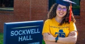 Graduation student smiling outdoors at Sockwell Hall campus.