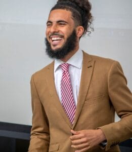 Bright smiling man in business suit with tie, professional appearance, and confident demeanor.