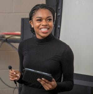 Professional woman presenter with microphone and tablet at conference.
