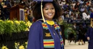 Graduation girl in cap and gown smiling at ceremony.