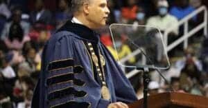 Graduation speaker delivering speech at university ceremony in academic regalia.