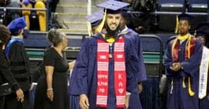 Graduation graduate in cap and gown at university ceremony, celebrating academic achievement.