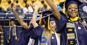 Graduates celebrating at a graduation ceremony in caps and gowns.