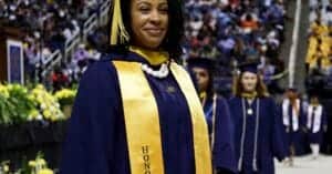 Graduation ceremony featuring a smiling graduate in a navy blue gown and gold honor sash at CAES New.