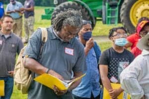 Engaged group of diverse people attending outdoor event, some wearing masks, with a focus on a man r.
