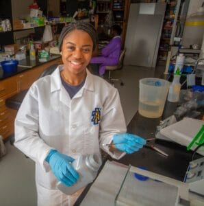 Young female scientist working in a laboratory with lab equipment and chemicals.