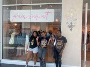 Empowered diverse youth posing outside a clothing store with a "movement" sign in the window.