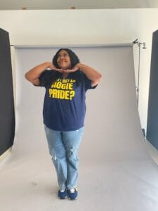 Bright young girl posing confidently in a photography studio with a white backdrop, wearing a navy T.