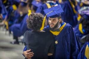 Graduation cap and gown celebration at university ceremony with smiling graduate and family member.