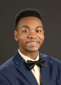 Young man in formal suit with bow tie smiling for professional portrait.