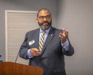 Engaged male speaker at a conference delivering a presentation on news and media topics.