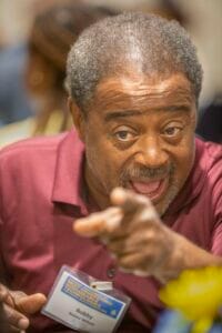 Engaged man pointing, speaking passionately at a conference or event.